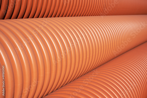 Close-up Stack of new orange polypropylene pipes. Plastic pipes for laying in the gutter. Industrial warehouse. photo