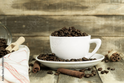 White cup with coffee beans on a wooden background