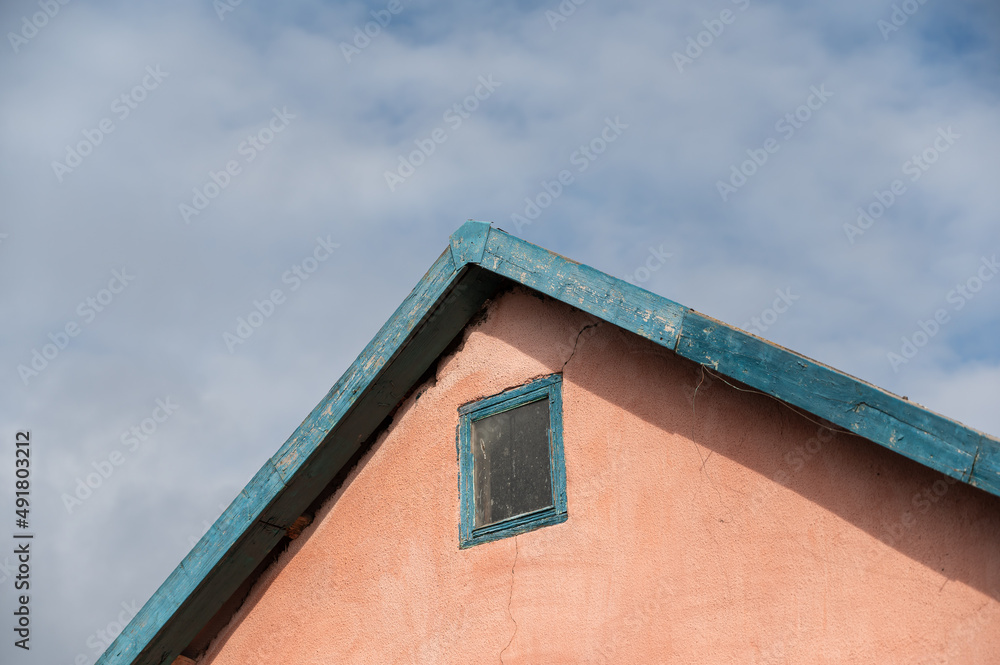 The top of the pink dwelling with a corner roof. A small structure against an overcast sky. The top of the pink dwelling with a corner roof. A small structure against an overcast sky.