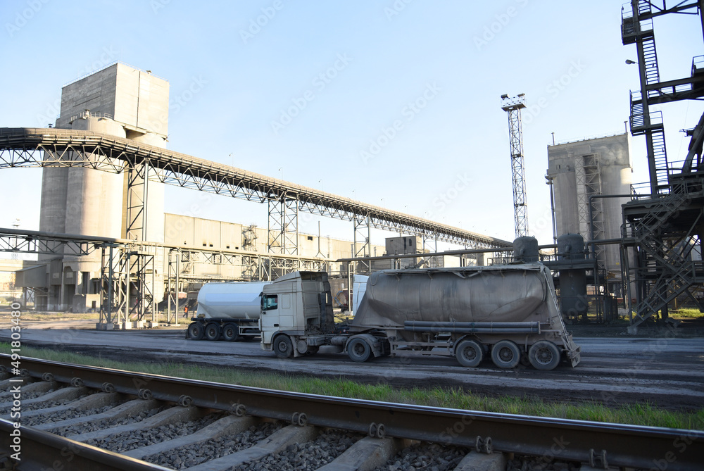 Truck with cement semi-trailer at cement plant site. Сement mix production at industrial factory. Industrial plant for the production of dry construction mixes. Concrete-mixing plant. Dry mix mortar. Truck with cement semi-trailer at cement plant site. Сement mix production at industrial factory. Industrial plant for the production of dry construction mixes. Concrete-mixing plant. Dry mix mortar.