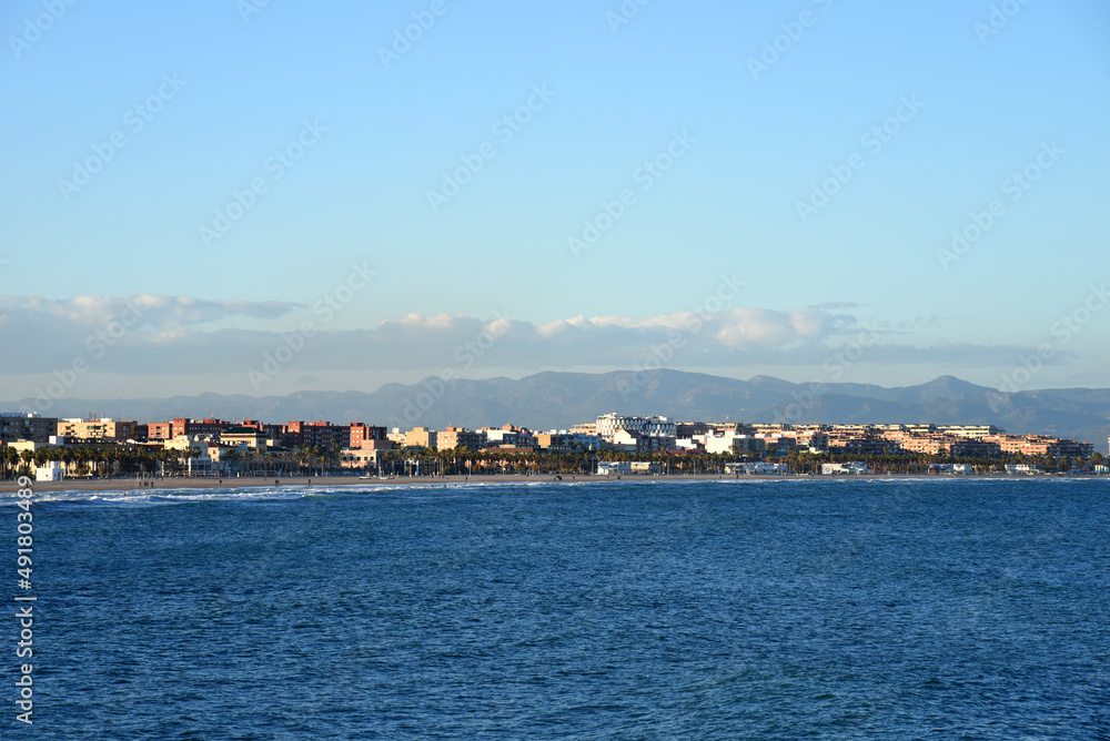 View on coastline and beach from La Marina de Valencia on the sea to the Las Arenas beach, Playa de las Arenas, Platja del Cabanyal and Playa de la Malvarrosa. Waves at sea on blue sky background.