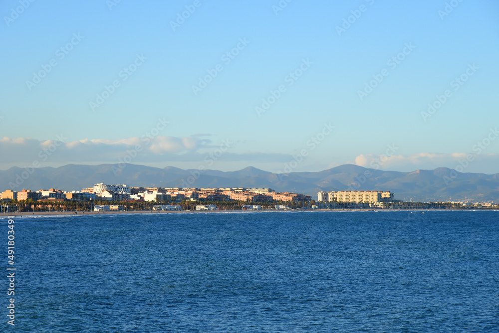 View on coastline and beach from La Marina de Valencia on the sea to the Las Arenas beach, Playa de las Arenas, Platja del Cabanyal and Playa de la Malvarrosa. Waves at sea on blue sky background.