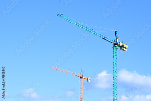 Tower crane against the blue sky. Tower crane on the construction of a residential building in Spain. Construction site with cranes for building construction. Сranes in action. Housing renovation 