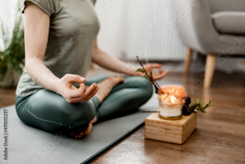 Foto Young relaxed woman doing yoga at home with candles and incense, close-up of han