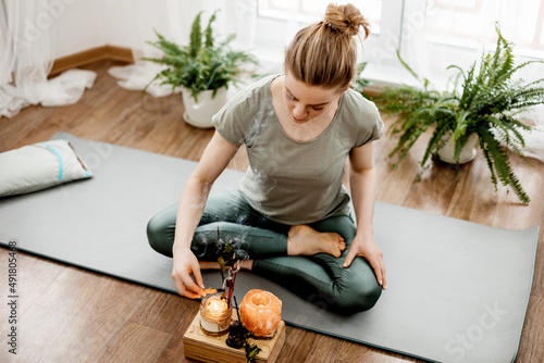 Young relaxed woman doing yoga at home with candles and incense photo