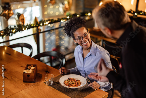 Smiling curly-haired African-American woman  thanking her polite waiter for the food.