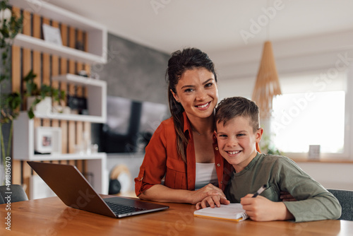 Mother's day, lovely portrait of mother and son, smiling for the photo, while studying.