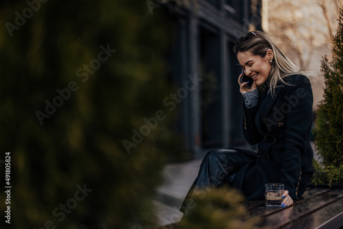 Joyful caucasian woman, having a conversation on phone, sitting on bench.