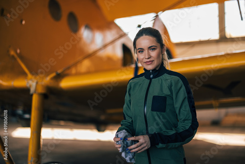 Obraz na plátně Portrait of confident female pilot in the suit, standing next to an airplane