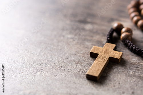 Rosary catholic cross on wooden table. Copy space photo
