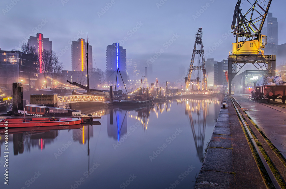 Fototapeta premium Rotterdam, The Netherlands, January 12, 2022: slowly dissappearing mist over Leuvehaven harbour on a morning in January