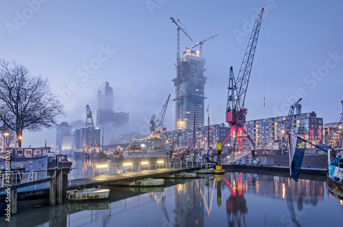 Rotterdam, The Netherlands, January 12, 2022: pontoon bridge, cranes and historic vessels at the maritime outdoor museum on a misty morning