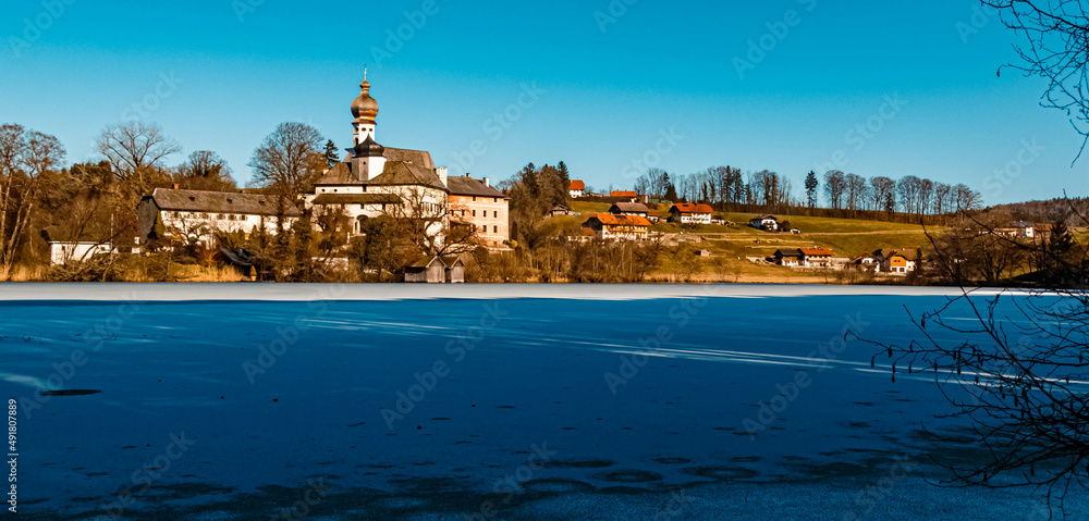 Beautiful winter wonderland with a monastery at the famous Hoeglwoerther See lake, Hoeglwoerth, Bavaria, Germany