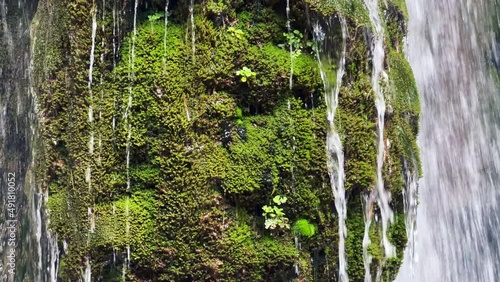 Waterfall in the forest with rocks covered in moss photo