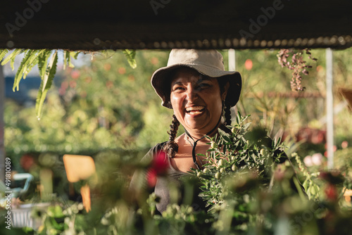 Obraz na plátne Short, heavy-set Latina woman working in her botanical garden with a hat on her head, very happy