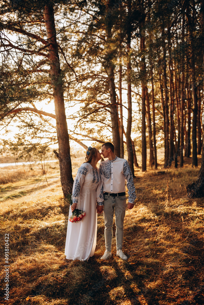 Fototapeta premium Bride and groom in Ukrainian national clothes. Wedding embroidered clothes. Wedding in the Ukrainian style. Happy bride in traditional Ukrainian embroidered dress. Ukrainian patriots