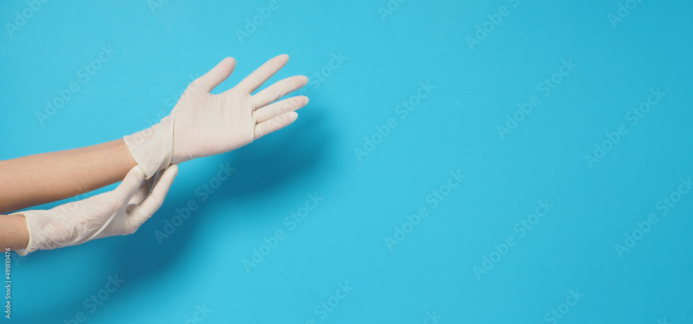 Two hand is wearing white surgical gloves or latex gloves on a blue background.