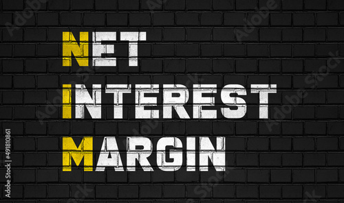 Net interest margin (NIM) concept,business abbreviations on black wall 
