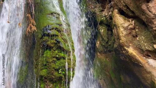 Waterfall in the forest with rocks covered in moss photo