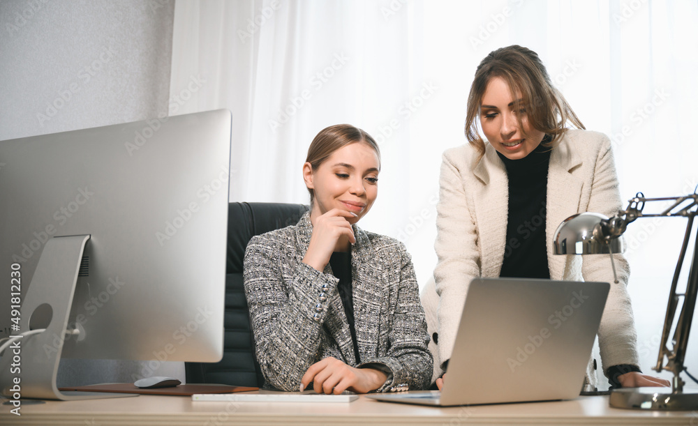 Attractive young adult women work together in the office at a meeting. A new employee consults with a mentor and presents a new project. Open space concept for teamwork Attractive young adult women work together in the office at a meeting. A new employee consults with a mentor and presents a new project. Open space concept for teamwork