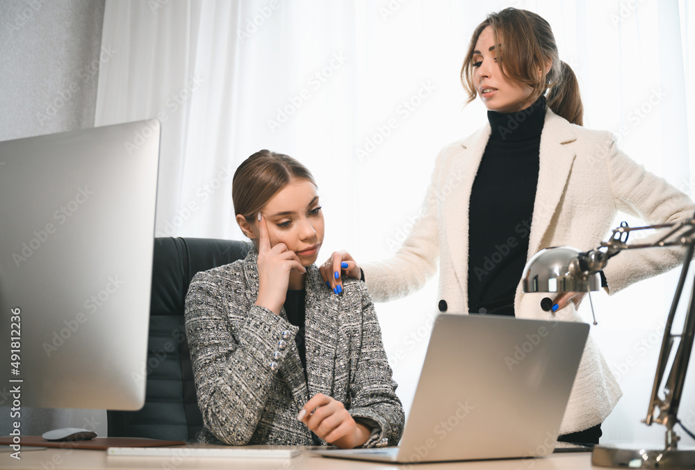 Attractive young adult women work together in the office at a meeting. A new employee consults with a mentor and presents a new project. Open space concept for teamwork Attractive young adult women work together in the office at a meeting. A new employee consults with a mentor and presents a new project. Open space concept for teamwork