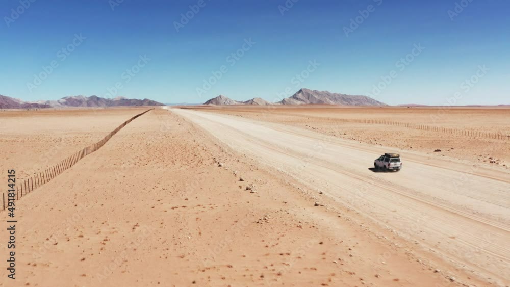 Land Vehicle Driving On Desert Landscape In Namibia On A Sunny Day. wide aerial drone Land Vehicle Driving On Desert Landscape In Namibia On A Sunny Day. wide aerial drone