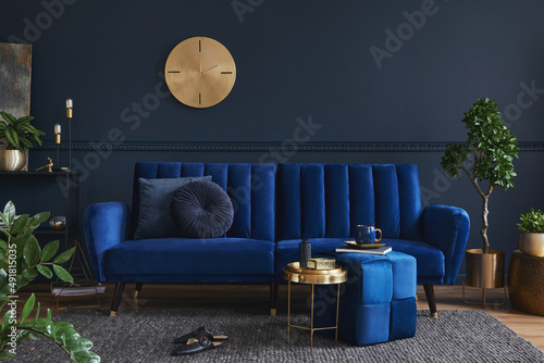 Stylowy, nowoczesny wystrój salonu z sofą w kolorze glamour, metalową półką, stolikiem kawowym, pufą i eleganckimi akcesoriami do domu. Ciemnoniebieska ściana. Home inscenizacja. Szablon. Skopiuj miejsce...