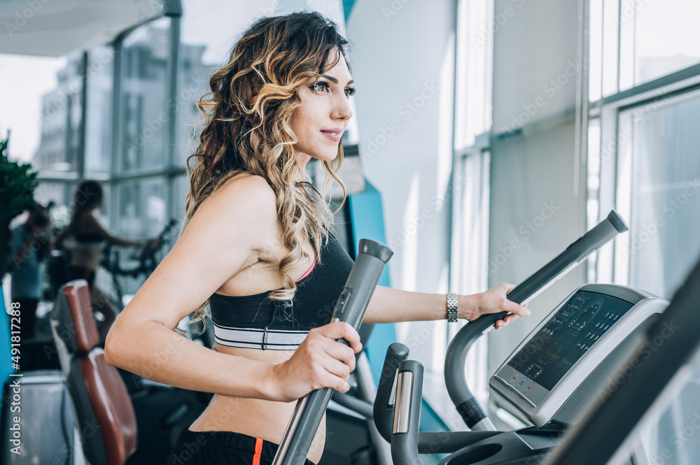 Attractive muscular smiling fitness woman running on treadmill in gym Attractive muscular smiling fitness woman running on treadmill in gym