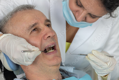 Male patient with open mouth receiving dental inspection at dentist's office