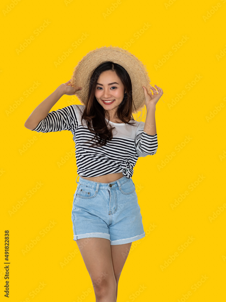 Happy young Asian woman tourist standing, ready for summer vacation travel trip, looking at camera, on yellow background. Happy young Asian woman tourist standing, ready for summer vacation travel trip, looking at camera, on yellow background.