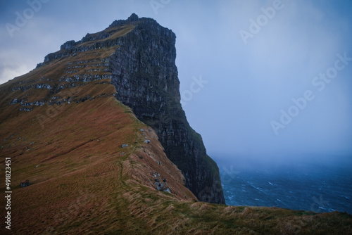 Kalsoy Island with Kallur lighthouse on on Faroe islands, Denmark, Europe. Clouds over high cliffs, turquoise Atlantic ocean and spectacular views. November 2021