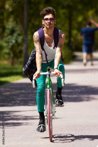 Riding on campus. Full length shot of a young guy cycling outdoors.
