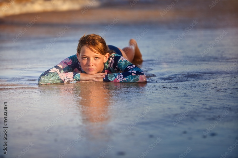 A young child relaxes in the water at the beach waiting for the waves