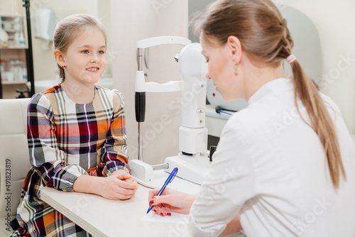 doctor interviews little girl before being examined in ophthalmologist s office.