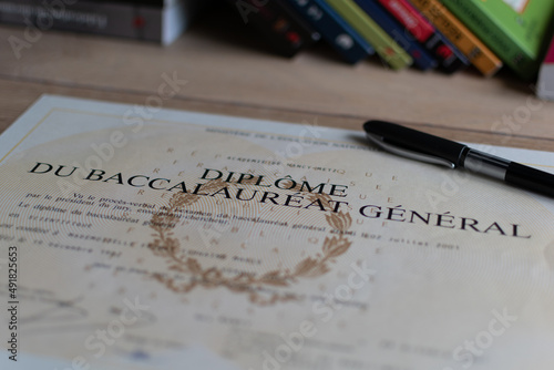 Baccalaureate : close up of a french diploma with some books, the text means general baccalaureate diploma