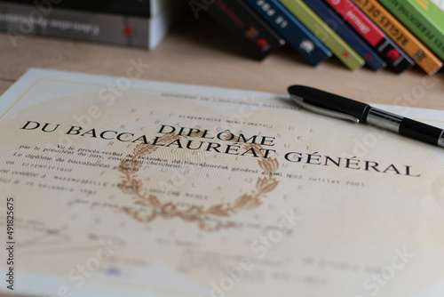 Baccalaureate : close up of a french diploma with some books, the text means general baccalaureate diploma photo