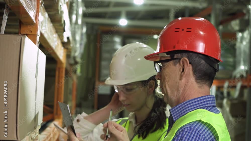 An elderly mentor and a young female storekeeper work together in the warehouse An elderly mentor and a young female storekeeper work together in the warehouse