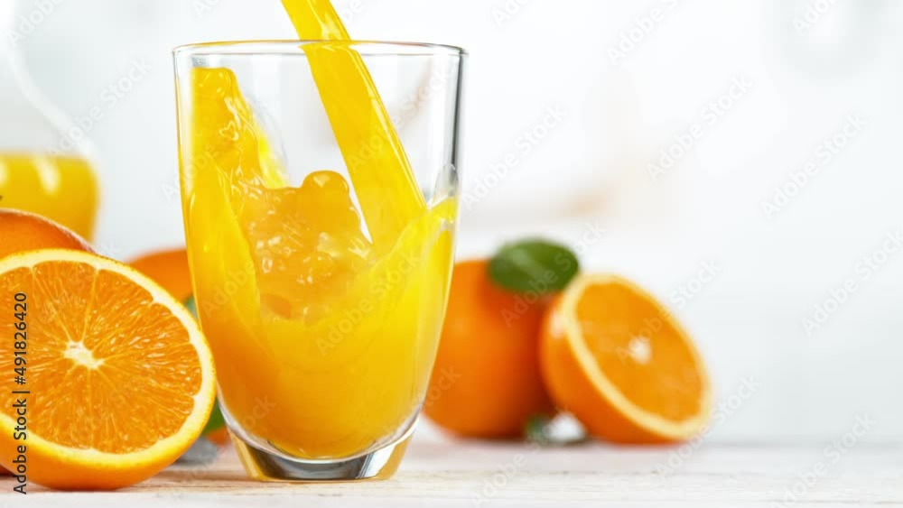Super slow motion of pouring orange juice into glass. Placed on white table with kitchen interior. Filmed on high speed cinema camera, 1000 fps. Speed ramp effect. Super slow motion of pouring orange juice into glass. Placed on white table with kitchen interior. Filmed on high speed cinema camera, 1000 fps. Speed ramp effect.