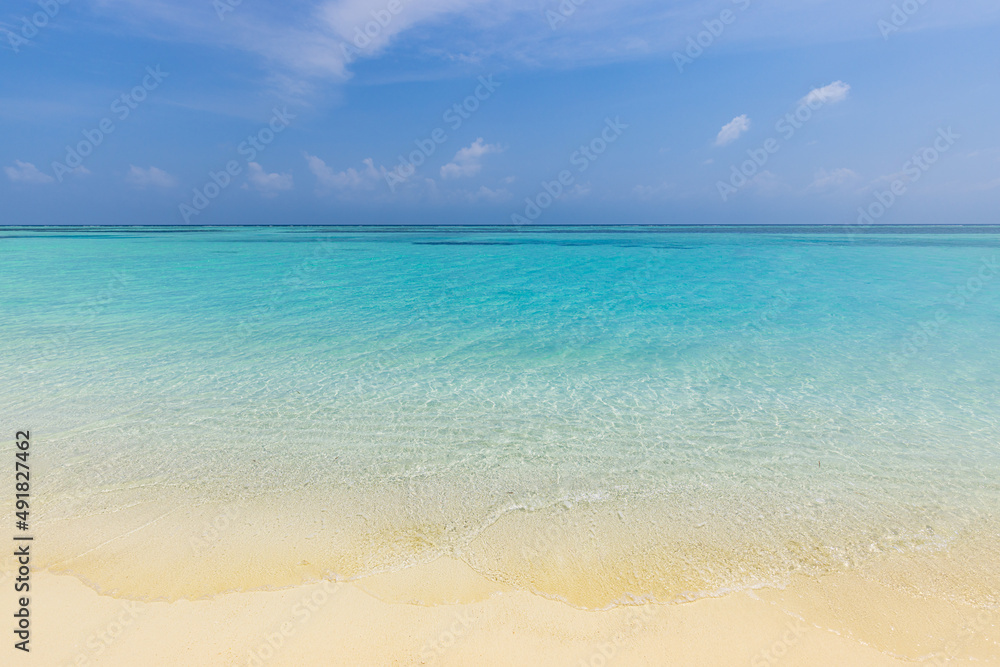 Closeup sandy beach waves and blue summer sky. Panoramic beach landscape. Empty tropical beach and seascape. Bright blue sky, soft sand, calmness, tranquil relaxing sunlight, summer mood