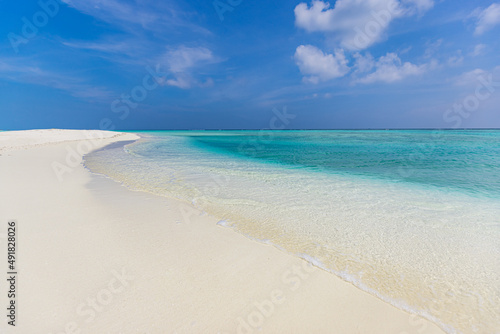 Closeup sandy beach waves and blue summer sky. Panoramic beach landscape. Empty tropical beach and seascape. Bright blue sky  soft sand  calmness  tranquil relaxing sunlight  summer mood