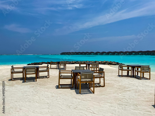 Maldives tropical beach with table and chairs on sea background 