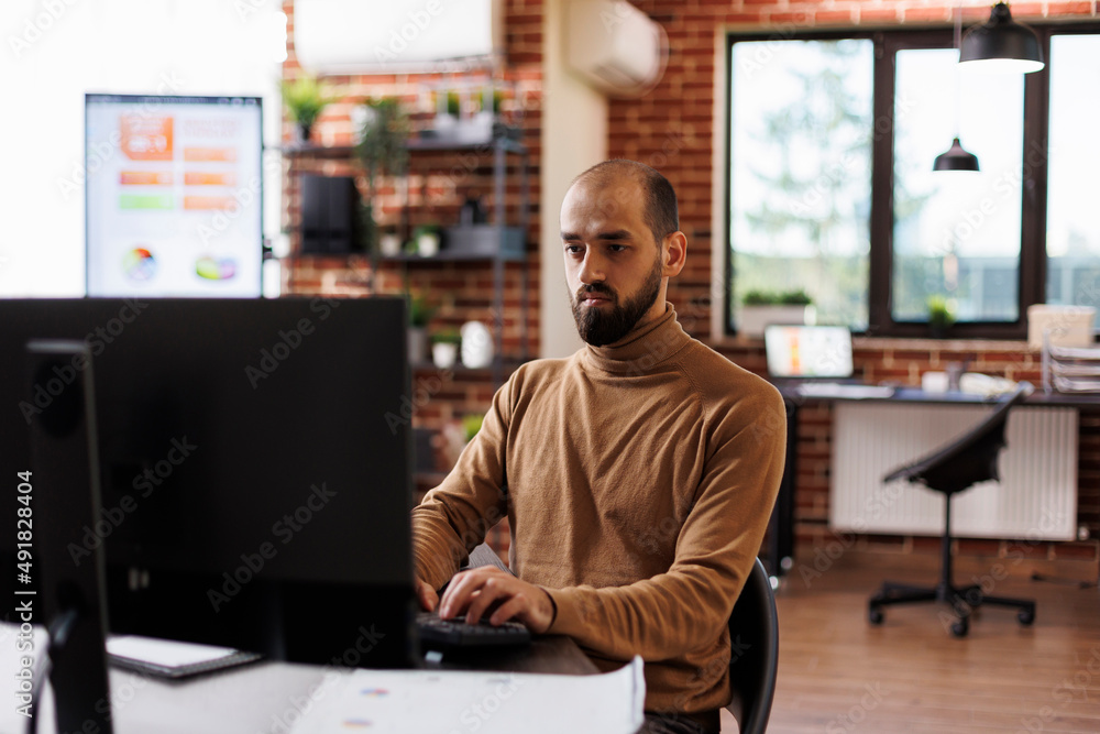 Agency accountant sitting in modern workplace while analyzing project presentation. Business company entrepreneur thinking about financial solutions while sitting at desk in office space.