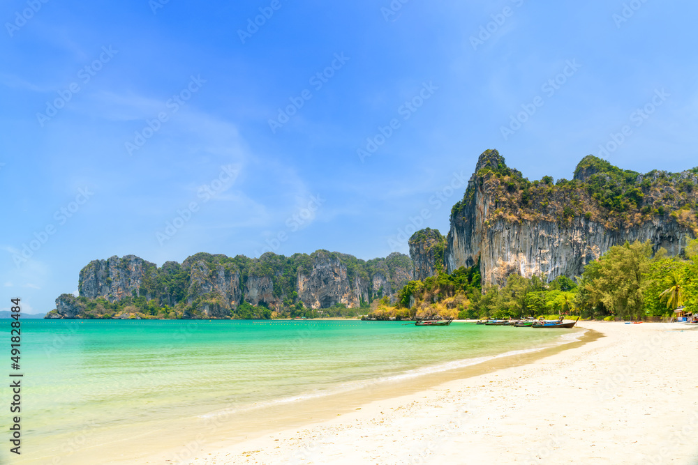 Obraz premium Railay beach west with exotic limestone cliff mountain and longtail wooden tourist boat, Krabi, Thailand
