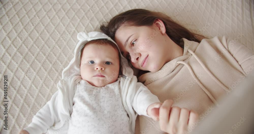 Newborn baby holds mom's hand while lying on the bed Newborn baby holds mom's hand while lying on the bed