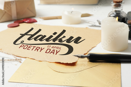 Paper sheet with text HAIKU POETRY DAY 17 APRIL and fountain pen with envelope on table
