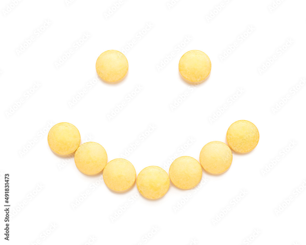 Happy smiley made of yellow pills on white background