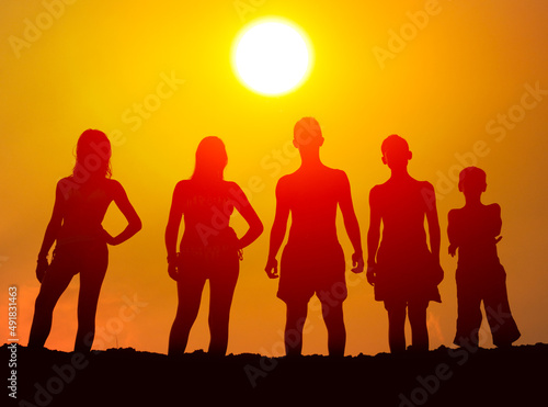Silhouettes of boys and girls on the beach at summer sunset