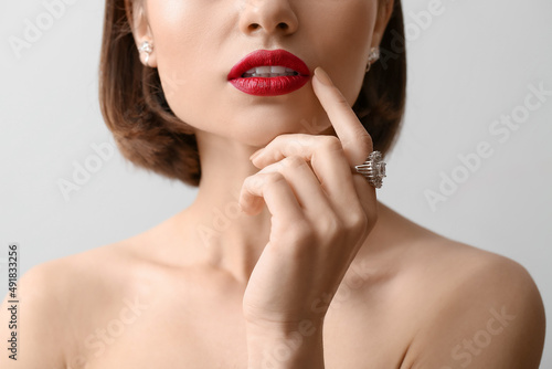 Woman with red lips and stylish jewelry on light background  closeup