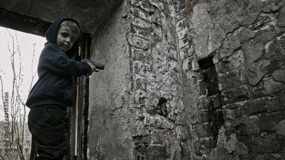 Child playing war in ruins 