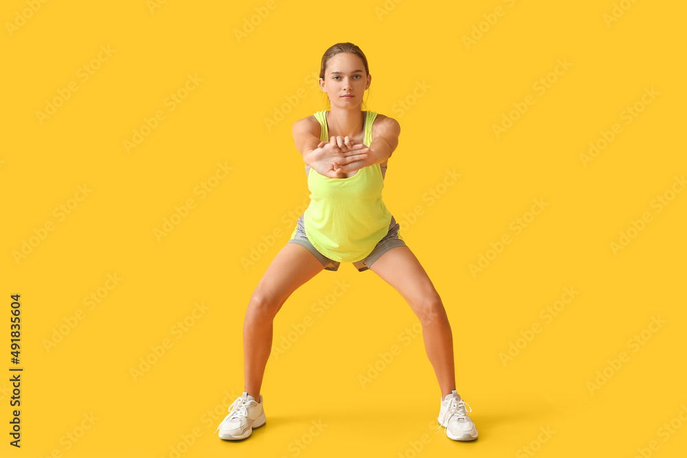 Sporty young woman training on yellow background